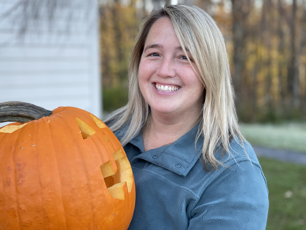 A parent smiles with a pumpkin
