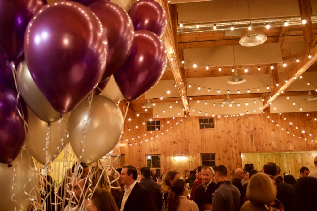 A picture of balloons and a dressed-up crowd at a parent social