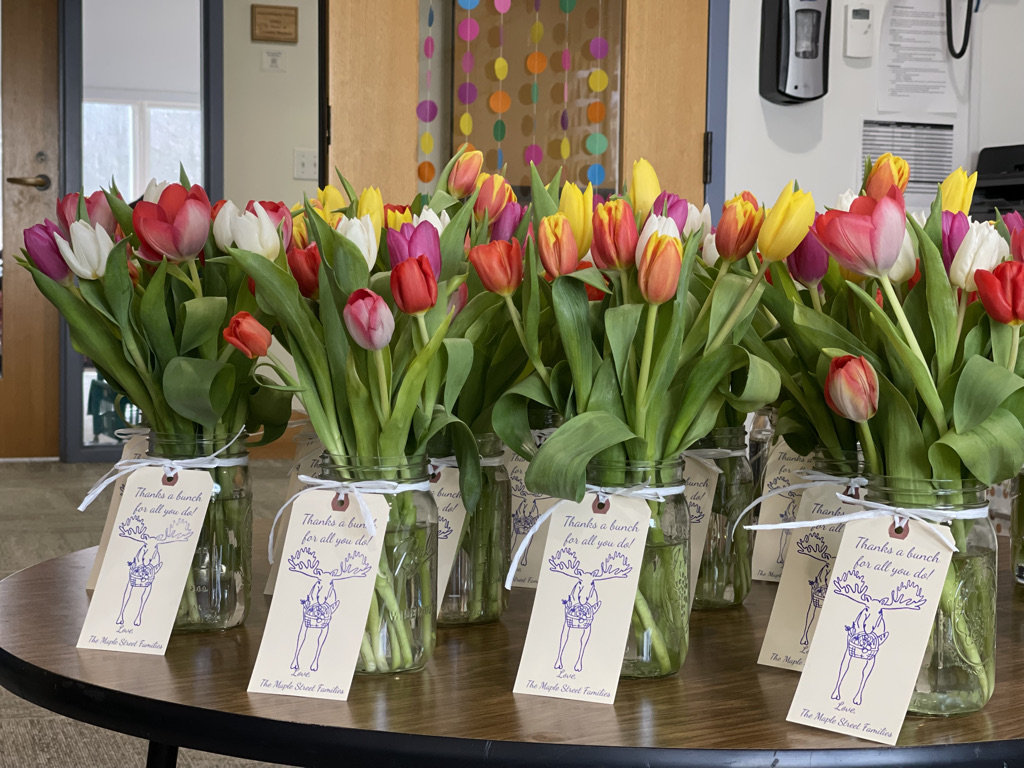Colorful tulips are arranged in vases with tags that say 
